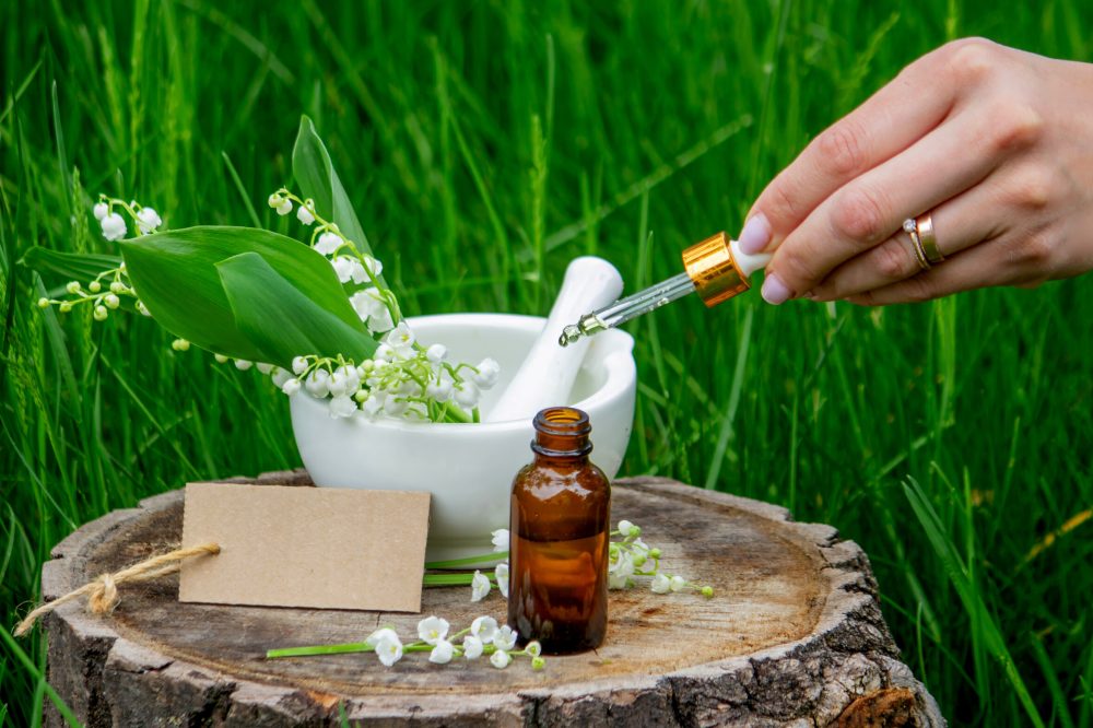 Glass bottle of lily of the valley essential oil with fresh flowers